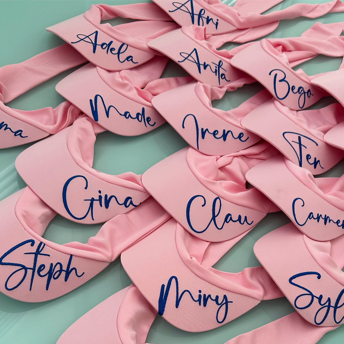 Viseras deportivas rosas personalizadas de Soledad García con nombres bordados y cierre de nudo